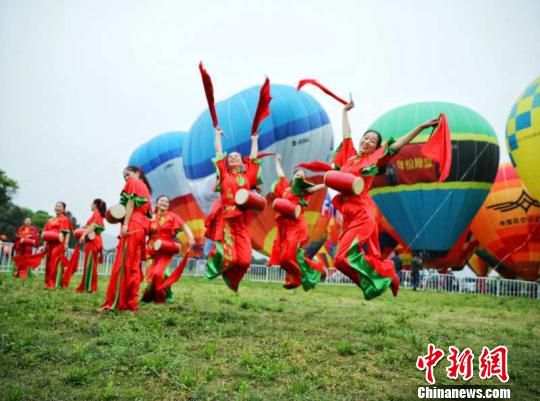 表演者在热气球前跳跃合影 张俊 摄