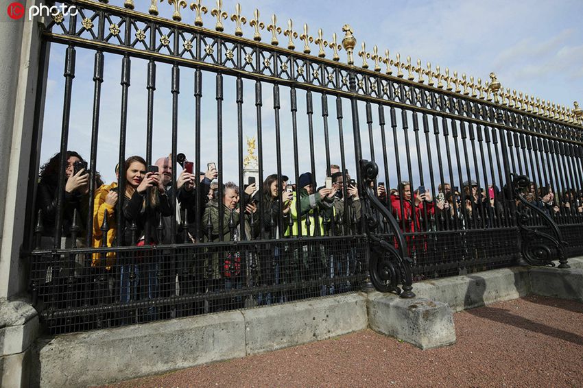 民众聚集在白金汉宫前，用手机拍摄宣布梅根王妃诞下男婴的公告架。(IC Photo版权作品 请勿转载)